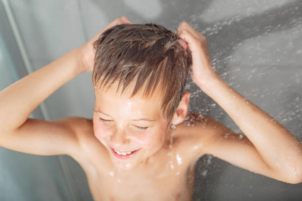 muchacho adolescente feliz lavado de cabeza en la ducha en el baño - shower child shampoo washing fotografías e imágenes de stock