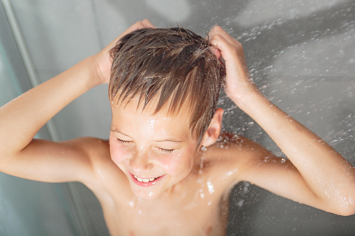 A Happy boy washing head in shower