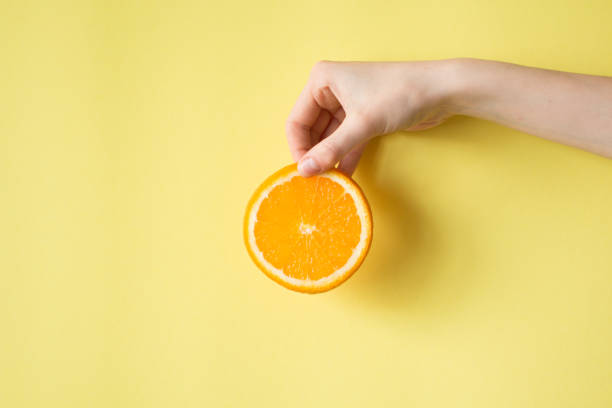istock Hand holding orange on yellow background food concept 854287972