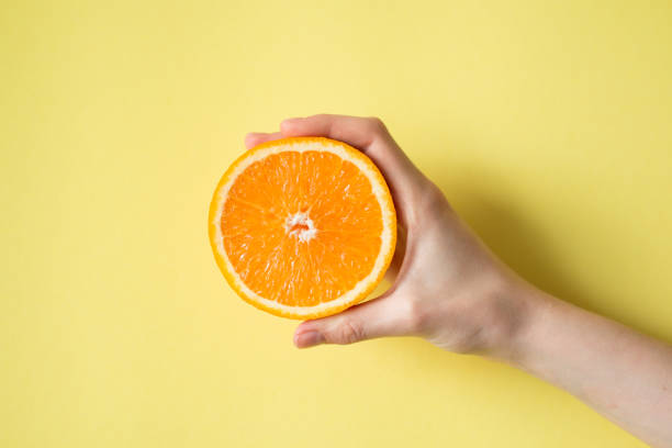 istock Hand holding orange on yellow background food concept 854288016