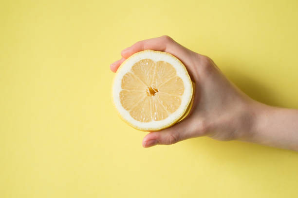 istock Lemon in woman's hand on a yellow background 854288256