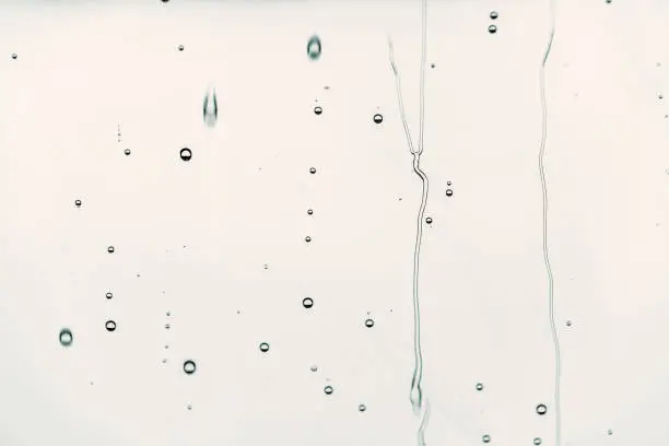 Photo of Rain drops on glass Flowing water, background is black color, selective focus.