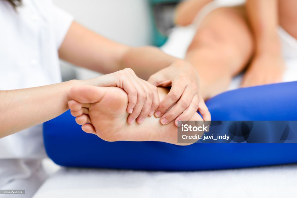 Medical massage at the foot in a physiotherapy center. Medical massage at the foot in a physiotherapy center. Female physiotherapist inspecting her patient. Foot Stock Photo