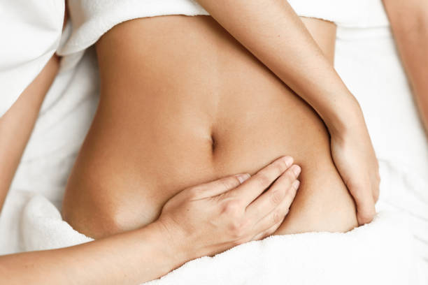 Hands massaging female abdomen.Therapist applying pressure on belly. stock photo