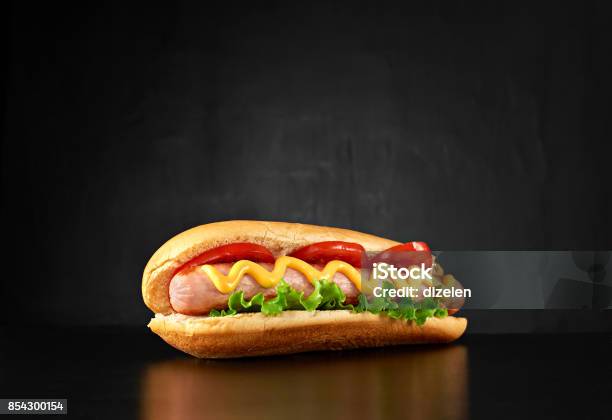 Big Hotdog With Sausage Tomatoes Mustard And Salad Isolated Stock Photo - Download Image Now