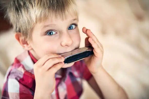 Happy little boy playing harmonica.
