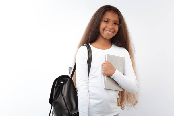 istock Pretty girl with backpack pressing notebook to her chest 854306142