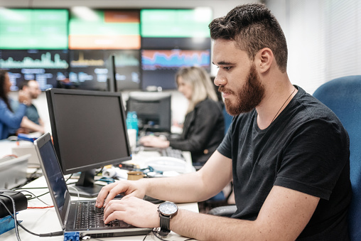 man working at laptop in big office with chart boards on the wall