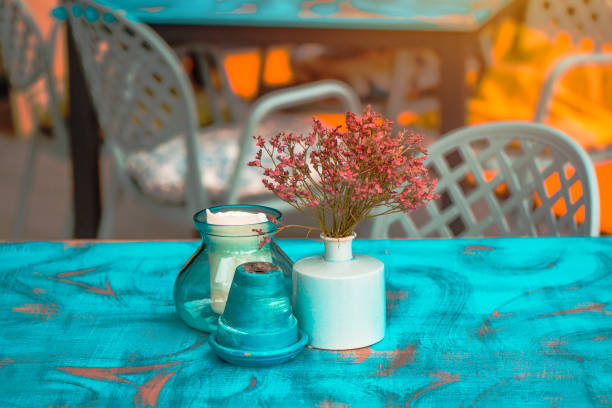 Modern hipster style teal and orange table arrangement in cafe or restaurant - flowers in pot, ashtray and candle