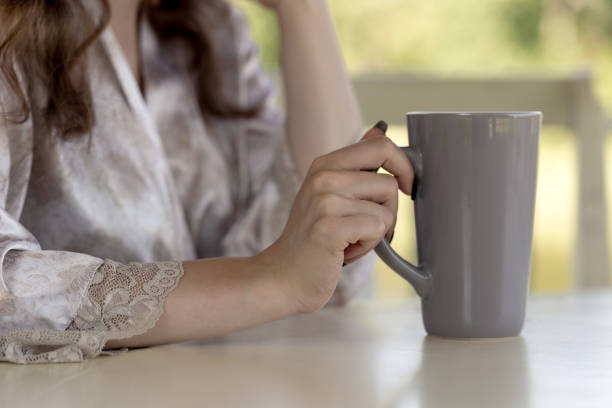 istock Woman's hands with long nails holding a big one-color gray cup. Light background. Pastel shades. 854320932