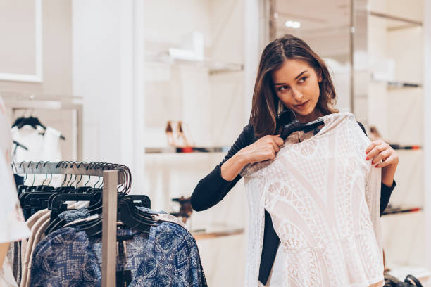 若い女性の店で服を選ぶ - boutique retail new elegance ストックフォトと画像