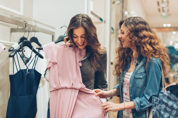 Look at this gorgeous dress! Two young women choosing dresses in a luxury fashion store boutique stock pictures, royalty-free photos & images