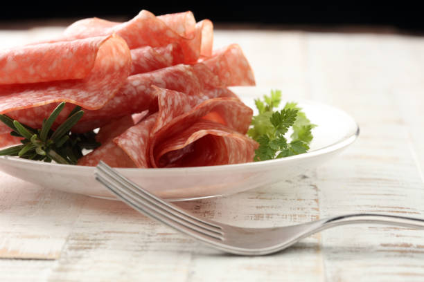 thinly sliced salami on a wooden texture on the background