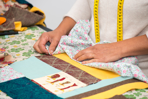 a close up of woman's hand sewing patchwork