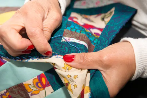 Photo of seamstress woman sewing for finish a quilt.