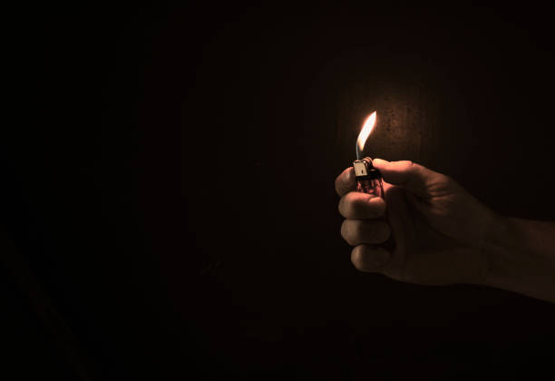 istock Hand holding lit lighter in the dark 854335812