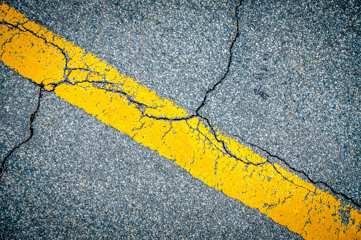 Closeup image of road marking and cracks in asphalt