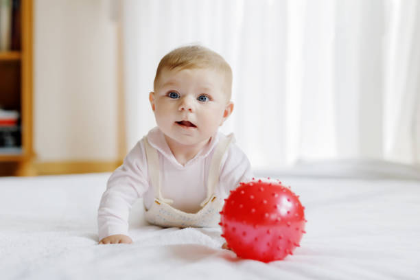 istock Cute baby playing with red gum ball, crawling, grabbing 854354644