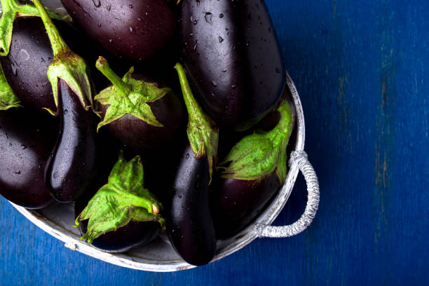 berenjenas frescas en cesta gris en mesa de madera azul. fondo rústico. vista superior. copia espacio. vegetales vegano. - berenjena fotografías e imágenes de stock