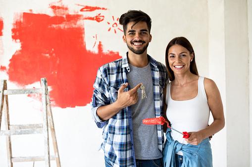 Smiling happy couple doing home renovation and holding key