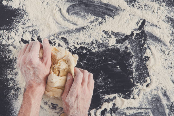 istock Hands top view knead dough on black background 854364086