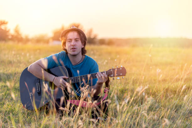 istock man playing the acoustic guitar in field 854368482