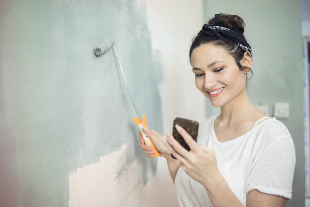 istock Happy young woman painting wall 854374098