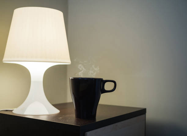 istock Mug with hot steam and lamp on side bed cupboard table, morning and inspiration idea concept background 854374818