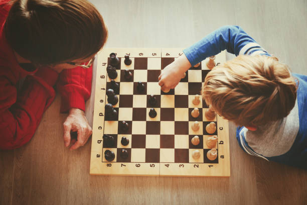 father and son play chess stock photo