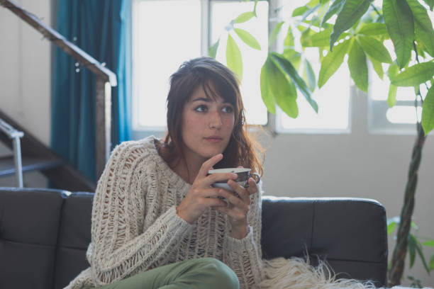 istock A woman sitting  on the couch, while looking forward and smiling 854382126