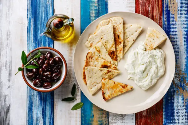Yogurt dip with herbs Dzadziki cacik sauce, Pita bread, Olive oil and Olives on wooden background
