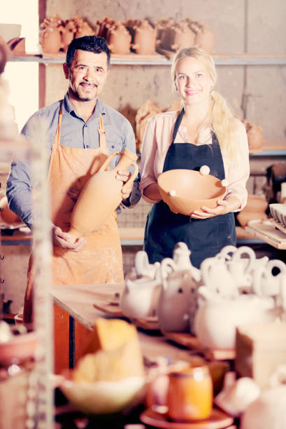 istock man and woman potters holding ceramic vessels in atelier 854385708