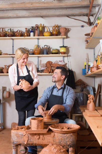 istock Positive craftsman talking to colleague in ceramics studio 854392506