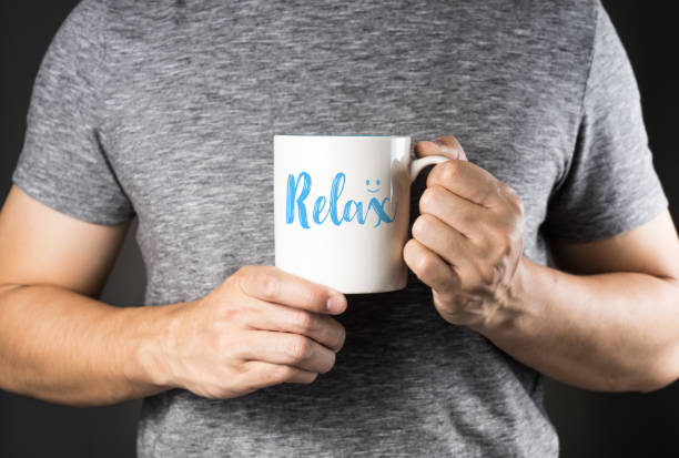 istock Asian man on gray t-shirt holding coffee mug with Relax text on it 854397264
