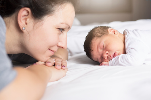 A Happy mother and baby lying on bed at home