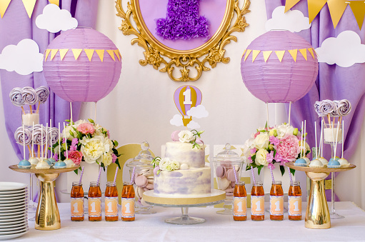 Interior decoration for a child's birthday is one year in purple colors. Candy, macaroon, tiered cake, and juices.