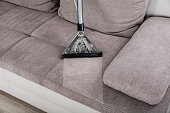 Woman Cleaning Sofa With Vacuum Cleaner