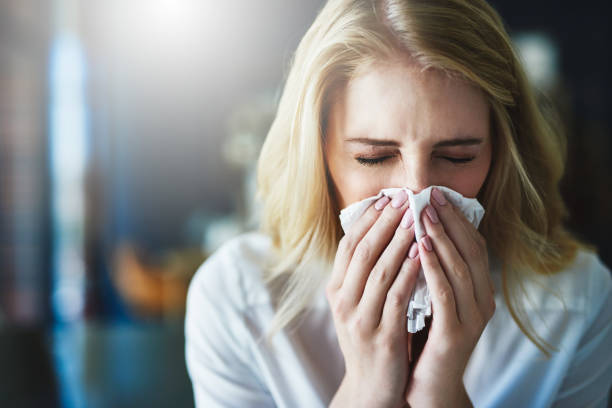 I hope this flu goes away quickly Shot of a frustrated businesswoman using a tissue to sneeze in while being seated in the office blowing nose photos stock pictures, royalty-free photos & images
