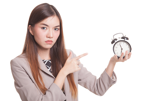 Angry young Asian woman point to a clock isolated on white background