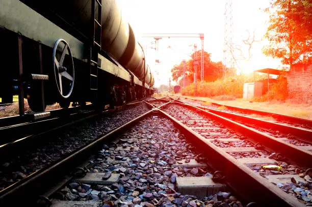 Freight train with petrol tank cars on the railroad station perspective view at the time of sunset.
