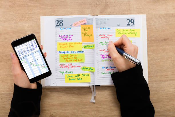 istock Businesswoman With Mobilephone Writing Schedule In Diary 854429698