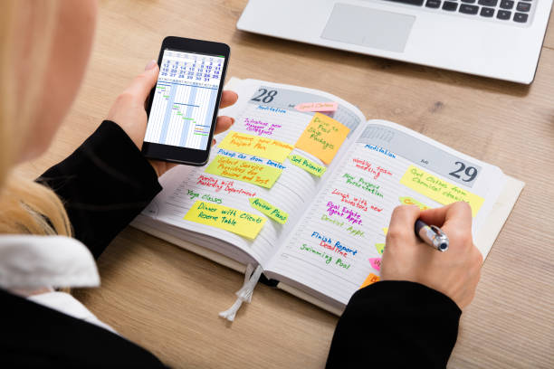 istock Businesswoman With Mobilephone Writing Schedule In Diary 854430924