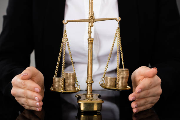 istock Lawyer's Hand Protecting Justice Scale With Coins 854440730