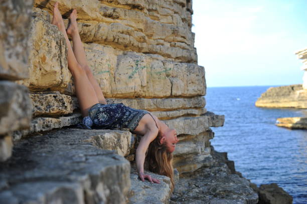 istock Young blonde women lying down posing on rocks 854441688