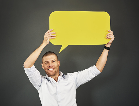 Studio shot of a man holding a speech bubble against a gray background