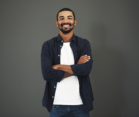 Studio portrait of a confident man posing against a gray background