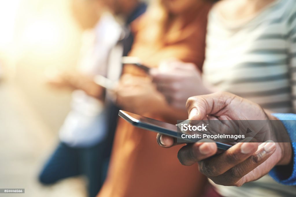 These days fingers do the talking Shot of an unrecognizable  group of people social networking outside Mobile Phone Stock Photo