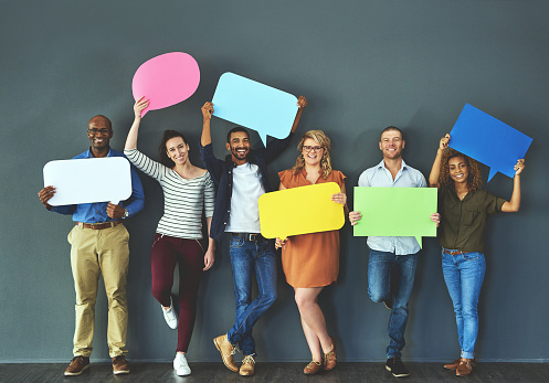 Studio shot of a diverse group of people holding up speech bubbles against a gray background
