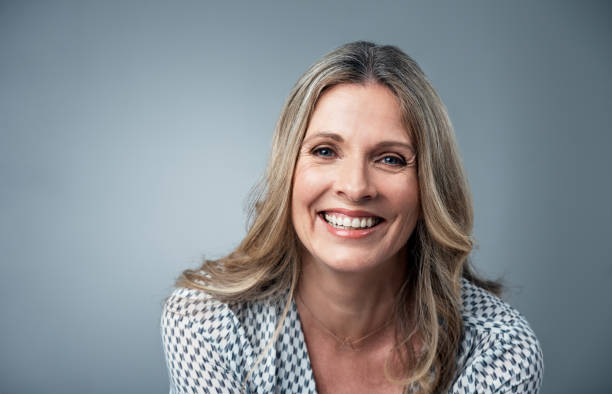 Her confidence just shines Studio portrait of an attractive and happy mature woman posing against a grey background older blonde woman stock pictures, royalty-free photos & images