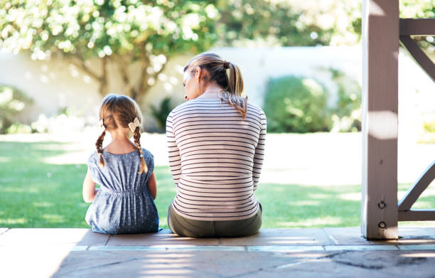 Life doesn’t come with a manual, it comes with mom Rearview shot of a young woman and her daughter having a conversation on the porch one parent photos stock pictures, royalty-free photos & images